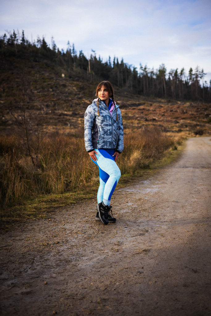 A person wearing a grey patterned puffer jacket with zipped pockets.